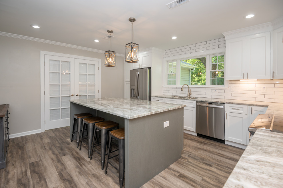 Trendy laminate floor kitchen photo in Other with white cabinets, a double-bowl sink, shaker cabinets, granite countertops, white backsplash, subway tile backsplash, stainless steel appliances and multicolored countertops