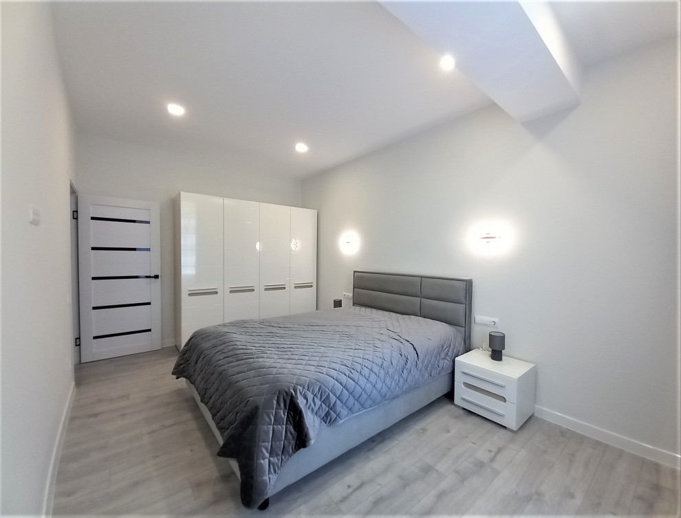 Ejemplo de dormitorio principal y gris y blanco actual de tamaño medio sin chimenea con paredes blancas, suelo laminado, suelo marrón y papel pintado