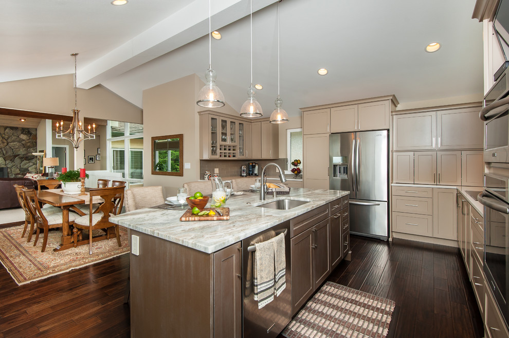 Photo of a transitional l-shaped open plan kitchen in Seattle with an undermount sink, shaker cabinets, beige cabinets, quartzite benchtops, stainless steel appliances, medium hardwood floors, with island and brown floor.