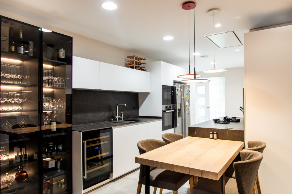 Large contemporary galley enclosed kitchen in Barcelona with a single-bowl sink, glass-front cabinets, black cabinets, black splashback, an island and grey worktops.