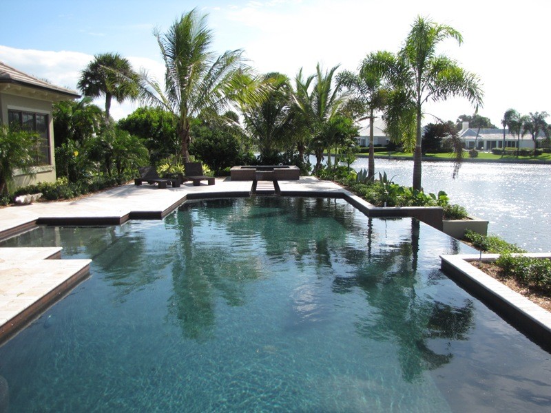 Example of a mid-sized minimalist backyard stone and rectangular natural pool design in Miami