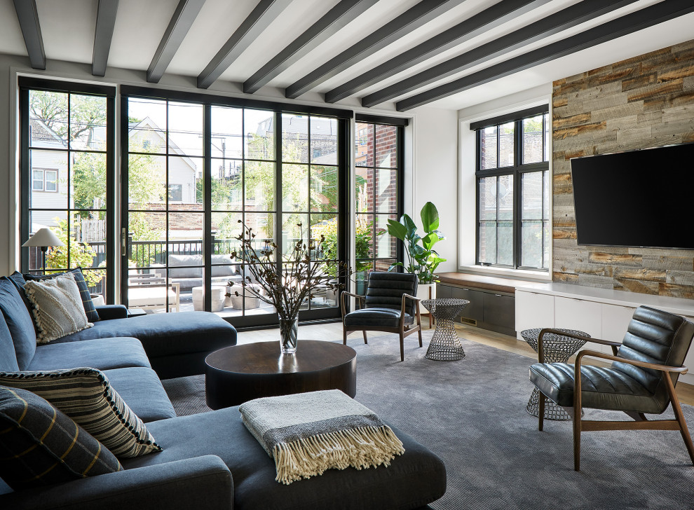 This is an example of a large contemporary living room in Chicago with white walls, light hardwood floors, a wall-mounted tv, beige floor and exposed beam.