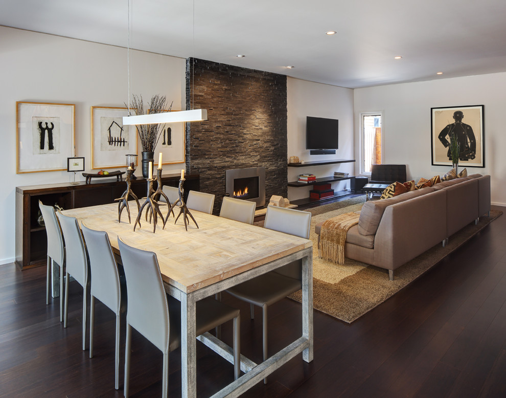 Photo of a mid-sized contemporary open plan dining in Milwaukee with dark hardwood floors, white walls, a ribbon fireplace, a metal fireplace surround and brown floor.