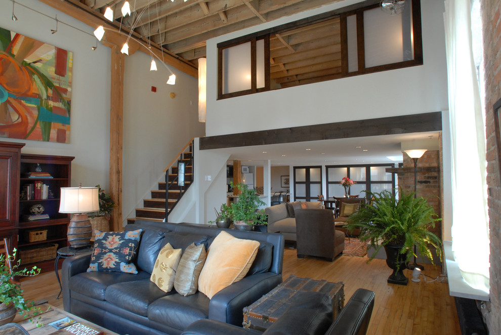 Photo of a large arts and crafts loft-style living room in Chicago with white walls, a standard fireplace and a brick fireplace surround.