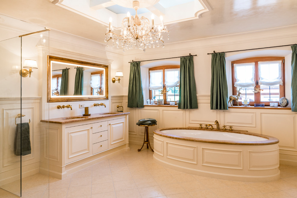 This is an example of a bathroom in Munich with raised-panel cabinets, white cabinets, a freestanding tub, white walls, an undermount sink, beige floor, a hinged shower door and brown benchtops.