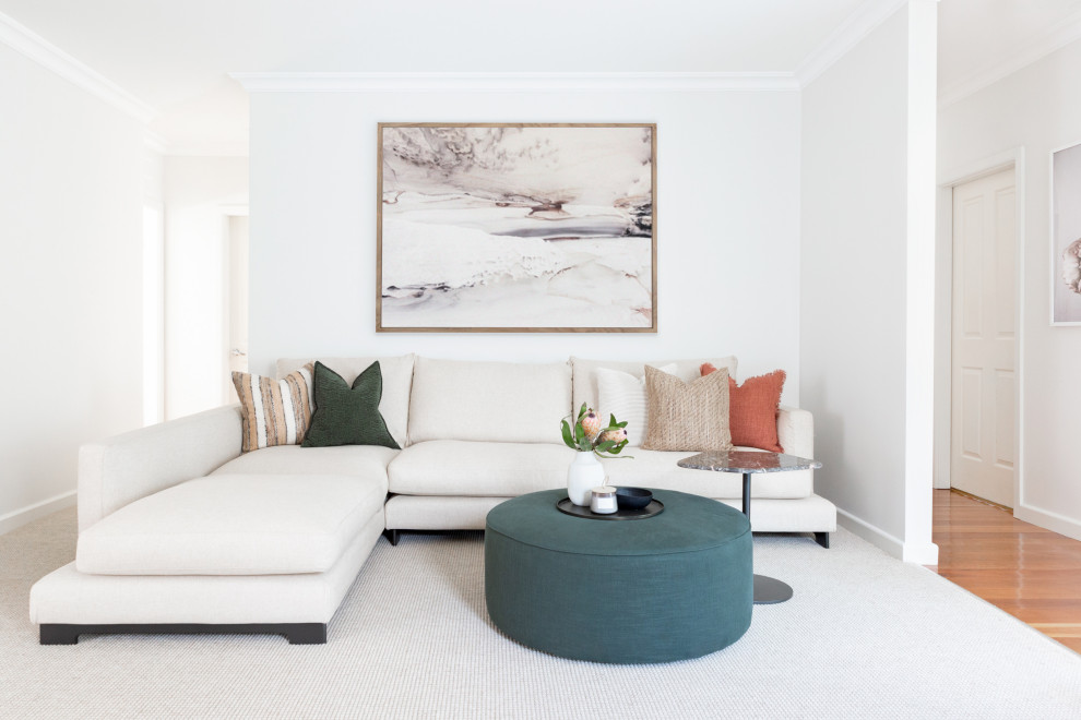 This is an example of a formal enclosed living room in Sydney with white walls, carpet, a freestanding tv and beige floor.