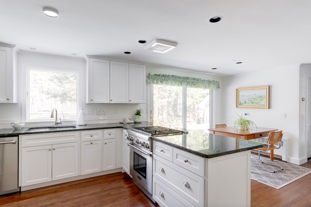 Inspiration for a mid-sized traditional u-shaped eat-in kitchen in Boston with a drop-in sink, recessed-panel cabinets, white cabinets, granite benchtops, black splashback, stainless steel appliances, medium hardwood floors, a peninsula and black benchtop.
