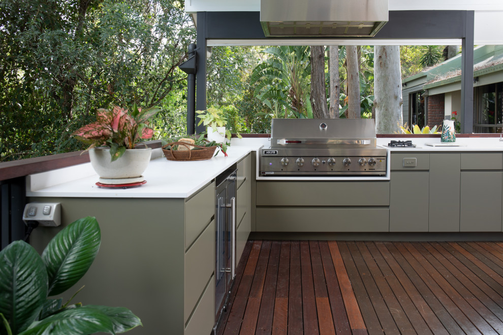 Photo of a mid-sized modern backyard and first floor deck in Brisbane with an outdoor kitchen, a roof extension and mixed railing.