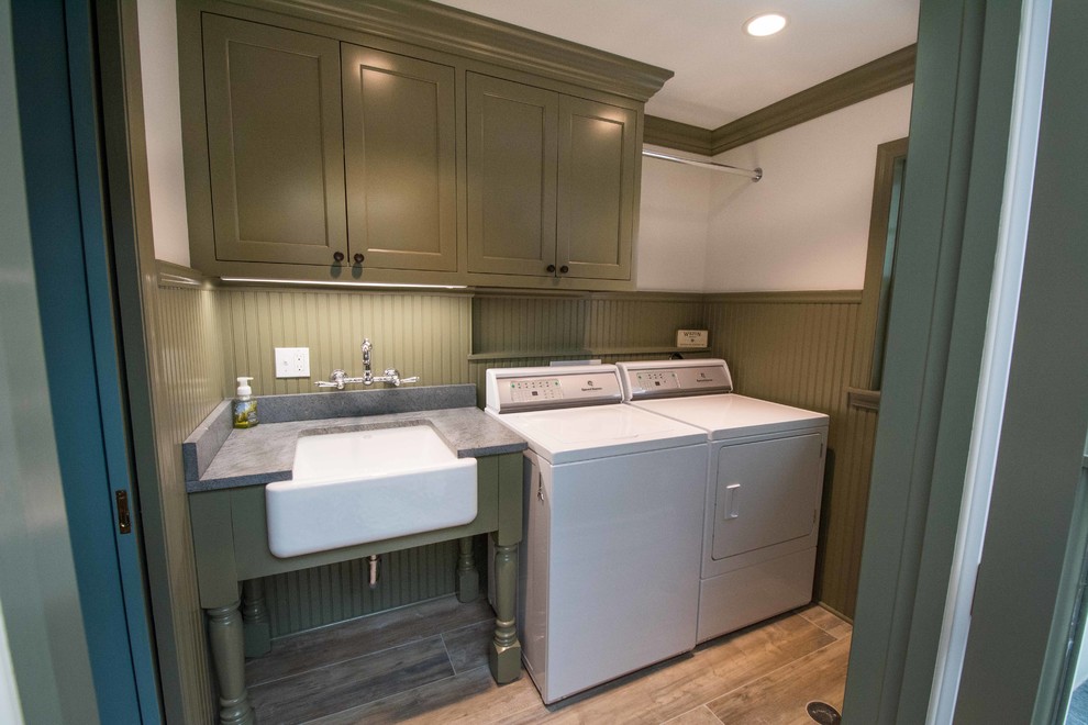 This is an example of a mid-sized traditional galley dedicated laundry room in New York with a farmhouse sink, beaded inset cabinets, green cabinets, soapstone benchtops, white walls, ceramic floors, a side-by-side washer and dryer and multi-coloured floor.