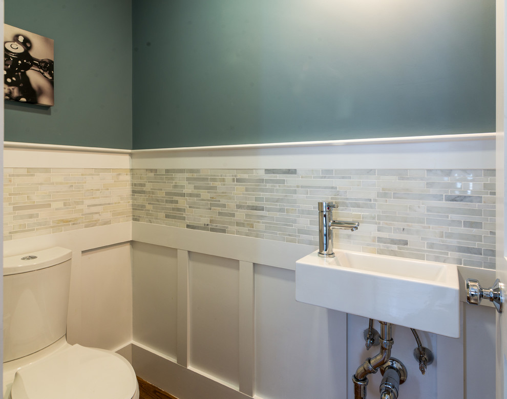 This is an example of a small transitional powder room in Boston with a one-piece toilet, gray tile, marble, green walls, dark hardwood floors and a wall-mount sink.