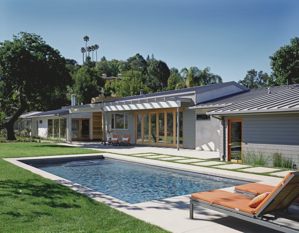 This is an example of a contemporary backyard rectangular pool in Los Angeles with concrete pavers.