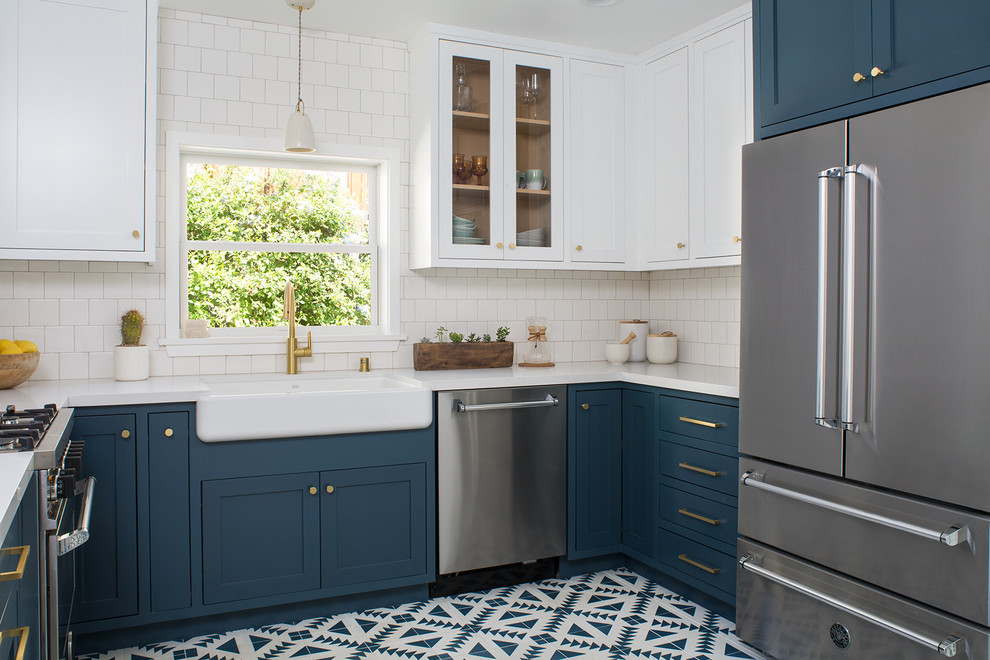 Photo of a mid-sized arts and crafts u-shaped kitchen in San Francisco with a farmhouse sink, shaker cabinets, blue cabinets, quartz benchtops, white splashback, ceramic splashback, stainless steel appliances, cement tiles, no island and blue floor.