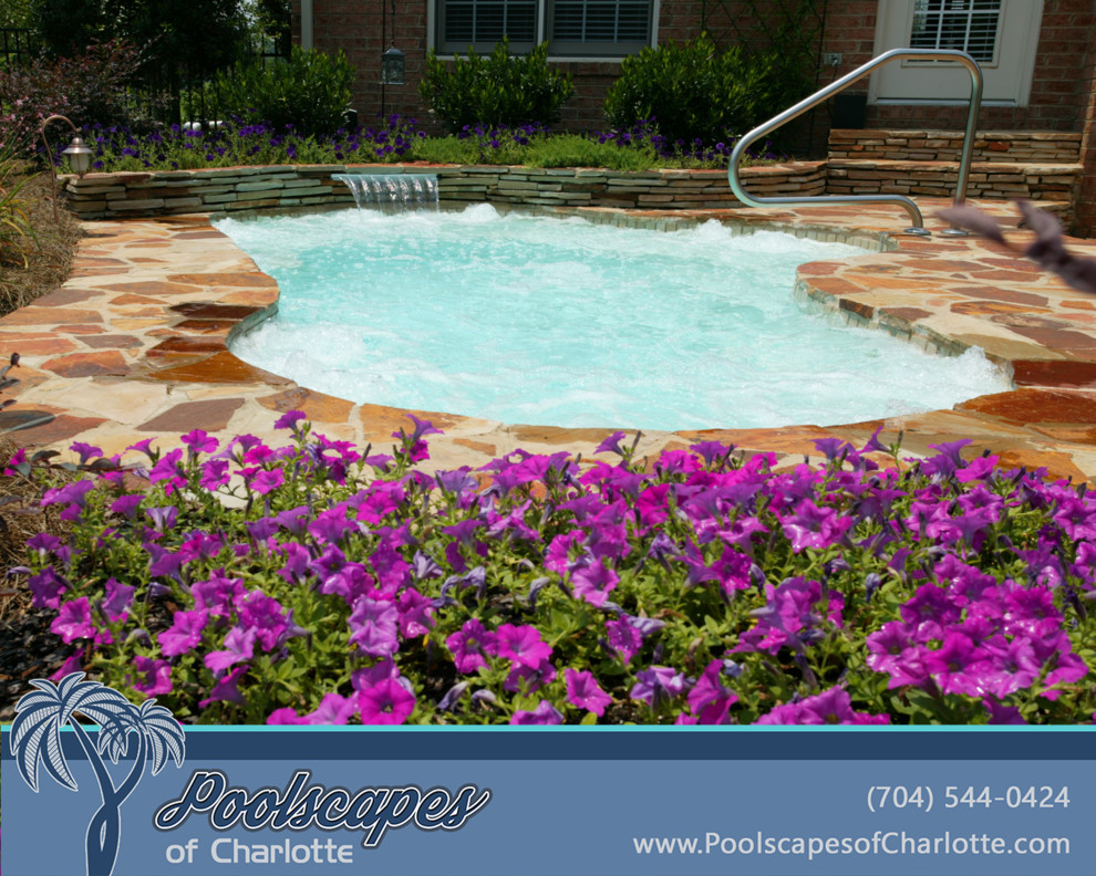 This is an example of a small traditional backyard custom-shaped pool in Charlotte with a water feature and decking.