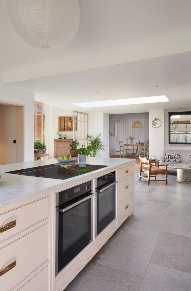 Design ideas for a large farmhouse grey and pink single-wall open plan kitchen in London with a belfast sink, shaker cabinets, pink cabinets, quartz worktops, pink splashback, black appliances, ceramic flooring, an island, multi-coloured floors, grey worktops and a vaulted ceiling.