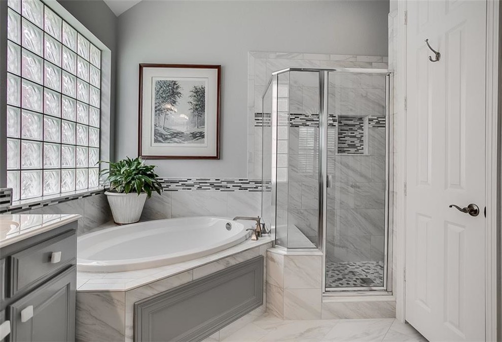 Inspiration for a mid-sized transitional master bathroom in Dallas with grey cabinets, a corner shower, matchstick tile, grey walls, an undermount sink, a hinged shower door, raised-panel cabinets, a corner tub, black and white tile, gray tile, multi-coloured tile, white tile, marble floors, white floor and white benchtops.