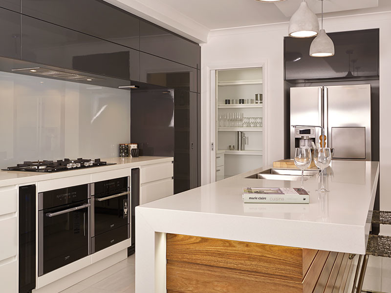Design ideas for a contemporary galley open plan kitchen in Other with an undermount sink, flat-panel cabinets, white cabinets, quartz benchtops, metallic splashback, mirror splashback, stainless steel appliances, vinyl floors, with island and brown floor.