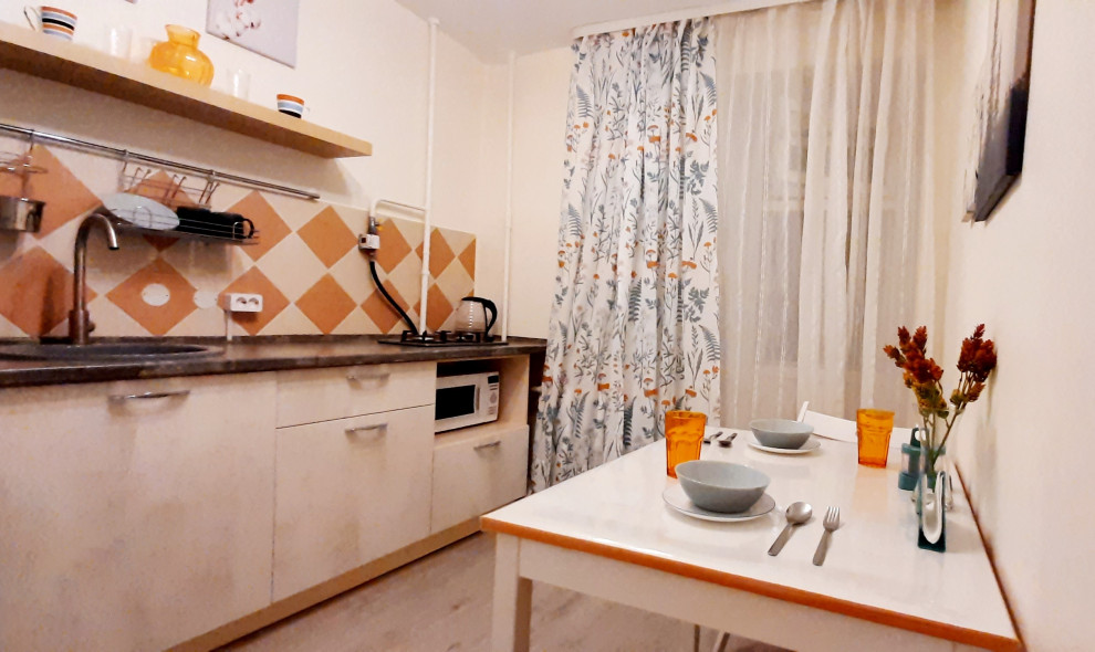 Photo of a small contemporary single-wall kitchen/diner in Other with a submerged sink, flat-panel cabinets, beige cabinets, orange splashback, ceramic splashback, medium hardwood flooring, beige floors and brown worktops.
