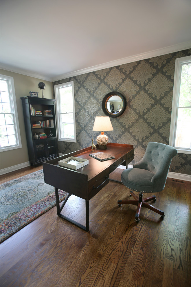 Mittelgroßes Klassisches Arbeitszimmer mit Arbeitsplatz, beiger Wandfarbe, braunem Holzboden, freistehendem Schreibtisch, braunem Boden und Tapetenwänden in Detroit