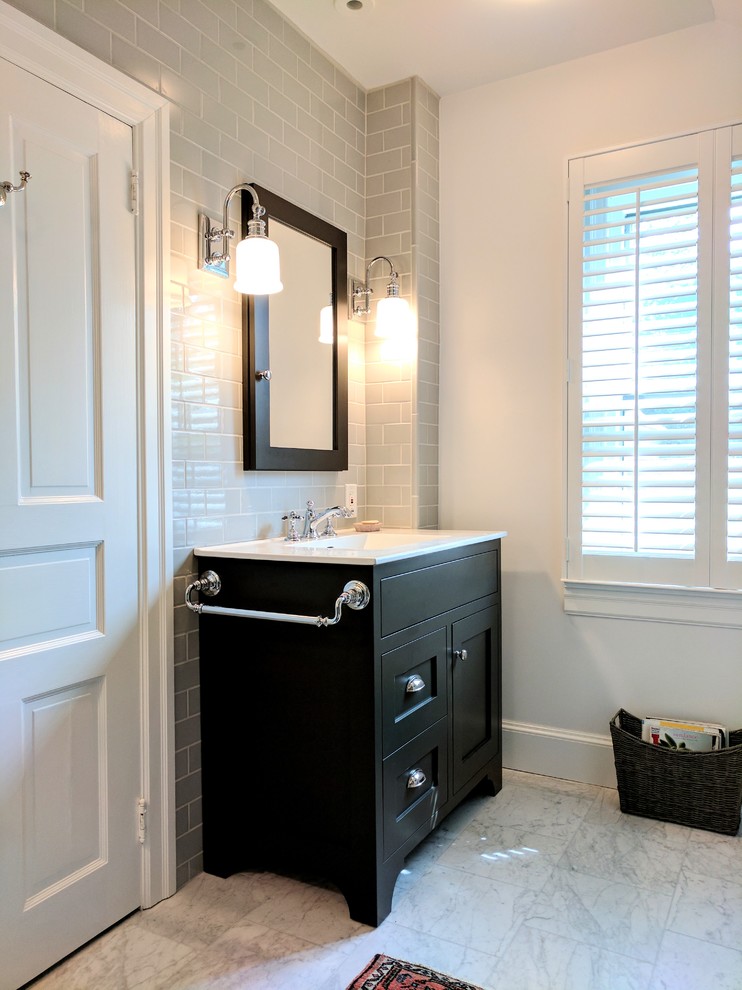 Photo of a small transitional master bathroom in Philadelphia with recessed-panel cabinets, black cabinets, an alcove tub, an alcove shower, a one-piece toilet, gray tile, ceramic tile, white walls, marble floors, an integrated sink, solid surface benchtops, grey floor and a hinged shower door.