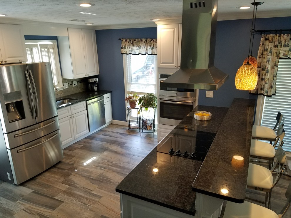 Eat-in kitchen - mid-sized transitional galley medium tone wood floor and beige floor eat-in kitchen idea in Atlanta with an undermount sink, raised-panel cabinets, white cabinets, quartz countertops, beige backsplash, subway tile backsplash, stainless steel appliances and a peninsula
