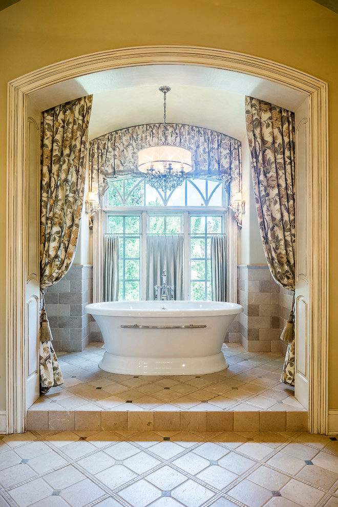Photo of an expansive traditional master bathroom in Other with furniture-like cabinets, light wood cabinets, a freestanding tub, a double shower, a one-piece toilet, beige tile, porcelain tile, yellow walls, porcelain floors, a drop-in sink and marble benchtops.