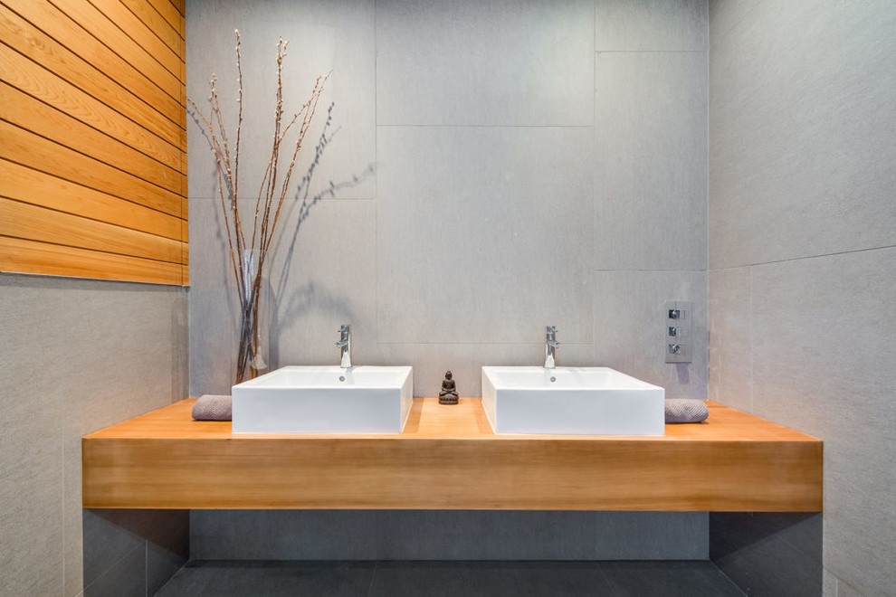 Design ideas for a small asian wet room bathroom in New York with medium wood cabinets, a wall-mount toilet, gray tile, porcelain tile, grey walls, porcelain floors, with a sauna, a vessel sink, wood benchtops, green floor and an open shower.