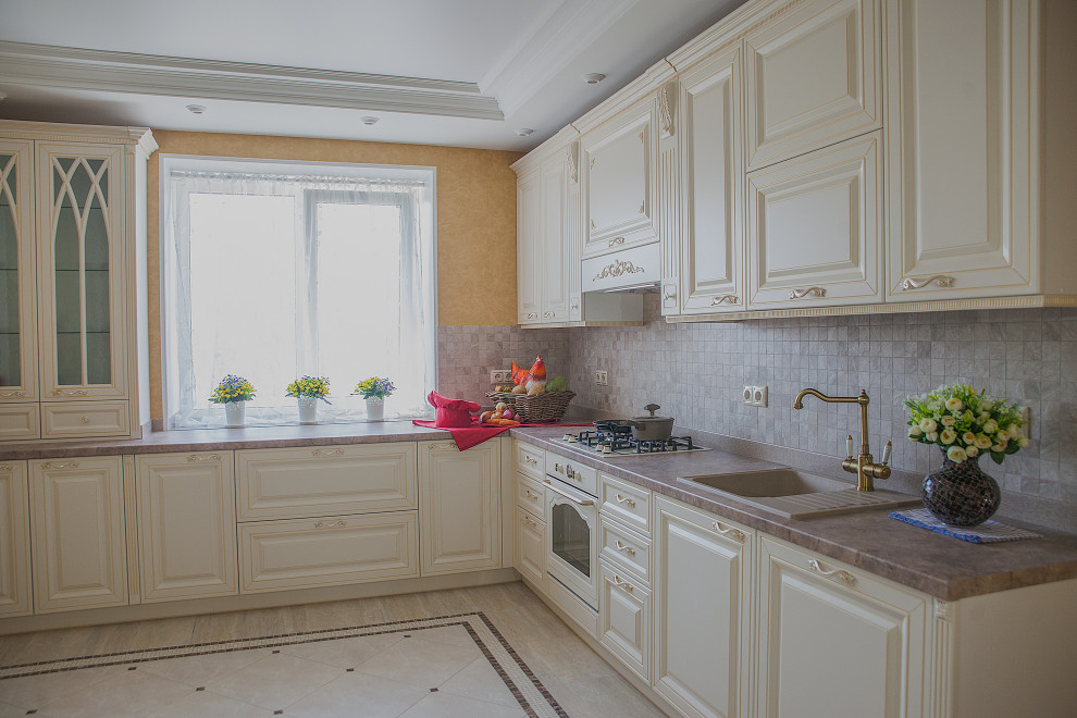 Large traditional l-shaped separate kitchen in Other with a drop-in sink, raised-panel cabinets, beige cabinets, solid surface benchtops, brown splashback, mosaic tile splashback, white appliances, ceramic floors, beige floor, brown benchtop and coffered.