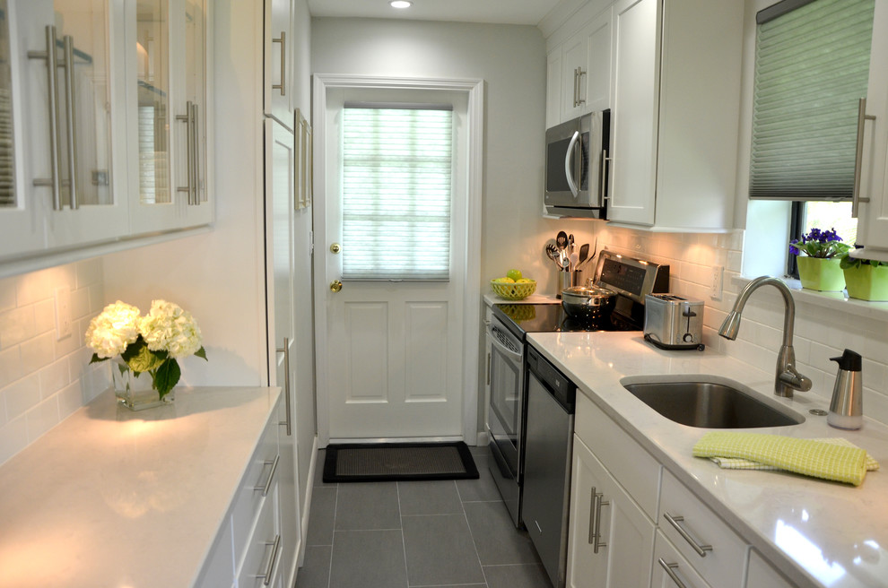Design ideas for a small transitional galley separate kitchen in Miami with an undermount sink, flat-panel cabinets, white cabinets, quartz benchtops, white splashback, subway tile splashback, stainless steel appliances and porcelain floors.