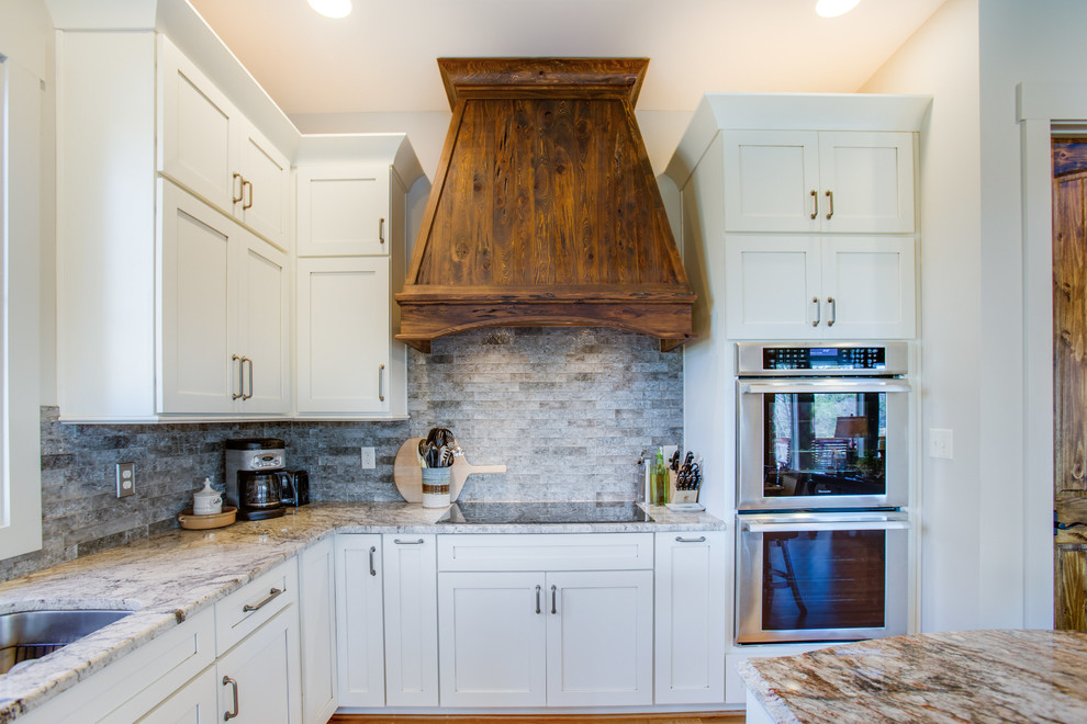 Mid-sized country l-shaped eat-in kitchen in Birmingham with shaker cabinets, white cabinets, granite benchtops, medium hardwood floors and with island.