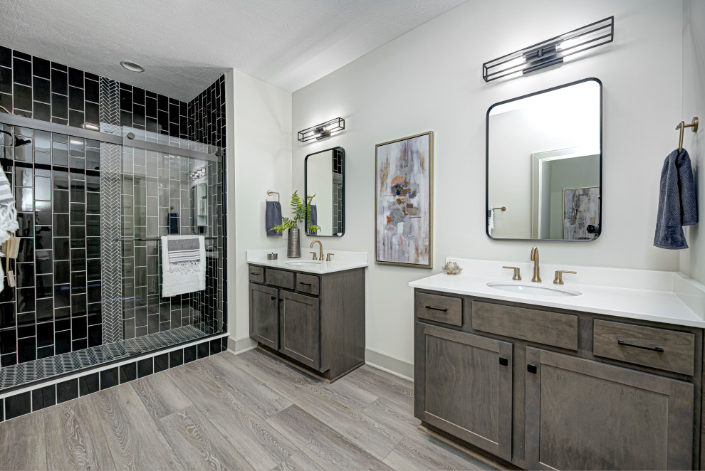 This is an example of a medium sized contemporary ensuite wet room bathroom in Indianapolis with shaker cabinets, black tiles, grey walls, a submerged sink, engineered stone worktops, a sliding door, white worktops, double sinks, a built in vanity unit, distressed cabinets, mosaic tiles, medium hardwood flooring and brown floors.