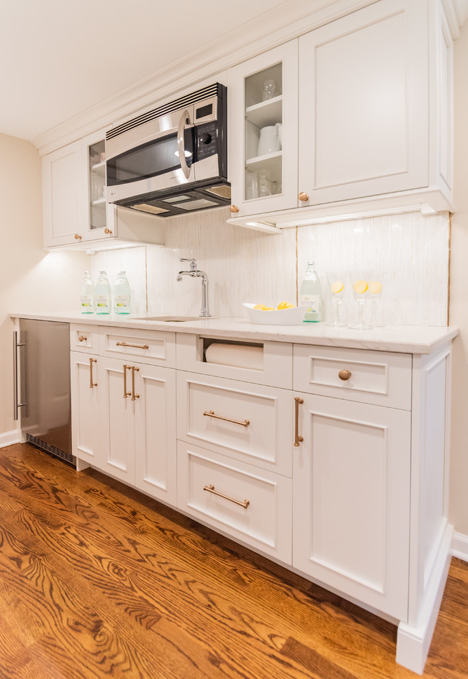 Inspiration for a mid-sized transitional single-wall wet bar in Philadelphia with an undermount sink, recessed-panel cabinets, white cabinets, white splashback, mosaic tile splashback and medium hardwood floors.