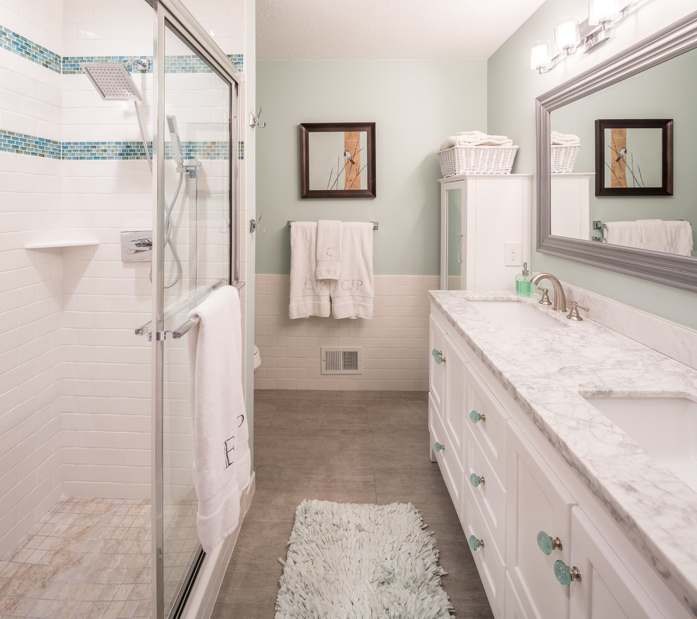 Photo of a mid-sized transitional master bathroom in Minneapolis with white cabinets, a freestanding tub, gray tile, ceramic tile, green walls, ceramic floors, an integrated sink, an alcove shower, a one-piece toilet, marble benchtops, beige floor and recessed-panel cabinets.