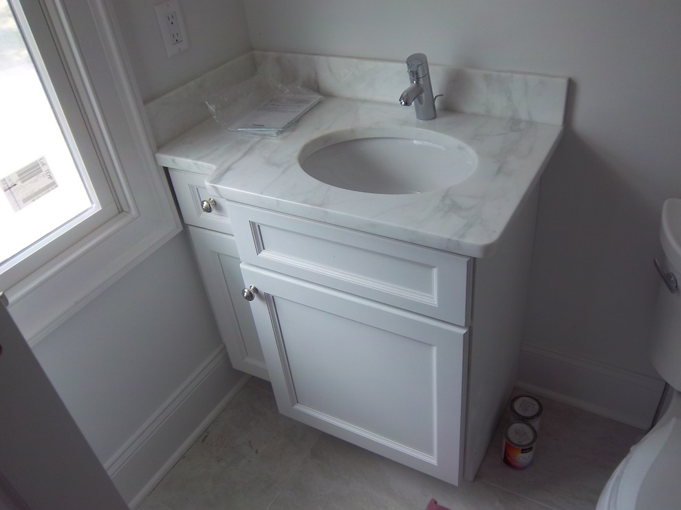 Example of a small transitional 3/4 white tile and marble tile ceramic tile and white floor bathroom design with shaker cabinets, white cabinets, a two-piece toilet, white walls, a drop-in sink and marble countertops