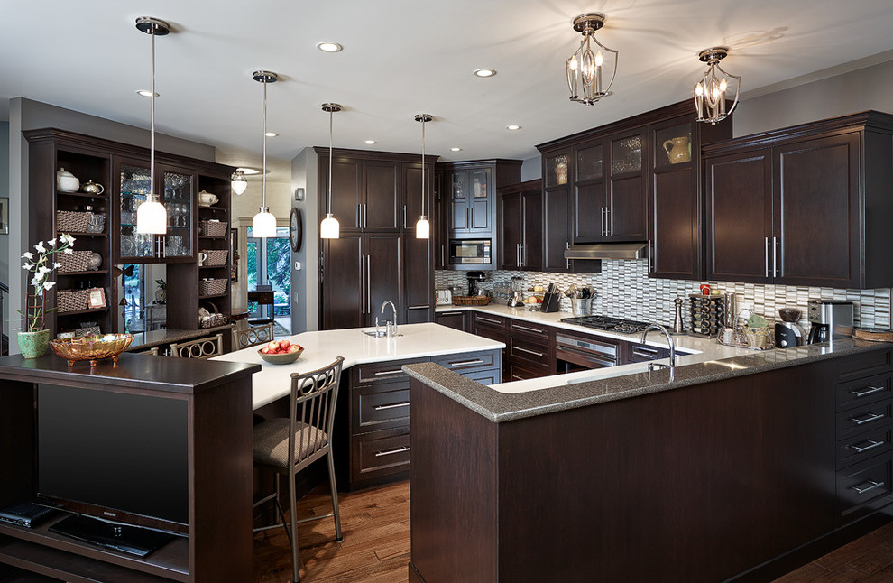 Inspiration for a large transitional u-shaped eat-in kitchen in Calgary with an undermount sink, shaker cabinets, dark wood cabinets, quartzite benchtops, light hardwood floors, with island, grey splashback, glass tile splashback and panelled appliances.