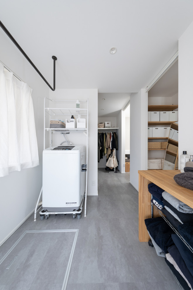 Photo of a mid-sized industrial dedicated laundry room in Other with white walls, vinyl floors, wallpaper and wallpaper.