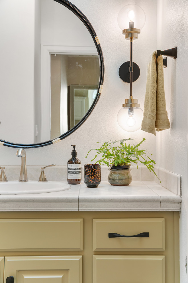 Exempel på ett mellanstort eklektiskt beige beige badrum med dusch, med luckor med upphöjd panel, gula skåp, ett badkar i en alkov, en dusch/badkar-kombination, en toalettstol med hel cisternkåpa, flerfärgad kakel, keramikplattor, vita väggar, klinkergolv i porslin, ett nedsänkt handfat, kaklad bänkskiva, flerfärgat golv och dusch med duschdraperi