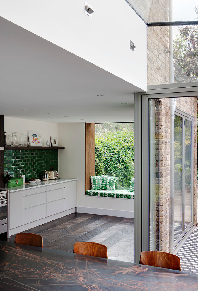 Eclectic kitchen in London with flat-panel cabinets, white cabinets, green splashback and subway tile splashback.