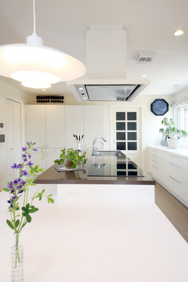 Photo of a large scandinavian l-shaped eat-in kitchen in Other with an undermount sink, flat-panel cabinets, white cabinets, white splashback, mosaic tile splashback, stainless steel appliances, ceramic floors and with island.