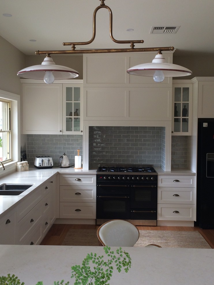 This is an example of a large country u-shaped separate kitchen in Wollongong with shaker cabinets, white cabinets, marble benchtops, green splashback, terra-cotta splashback and black appliances.