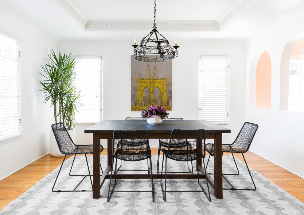 This is an example of a transitional dining room in Los Angeles with white walls, medium hardwood floors and brown floor.
