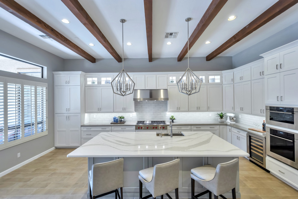 Eat-in kitchen - large transitional l-shaped porcelain tile and brown floor eat-in kitchen idea in Phoenix with a farmhouse sink, shaker cabinets, white cabinets, quartz countertops, white backsplash, subway tile backsplash, stainless steel appliances, an island and gray countertops