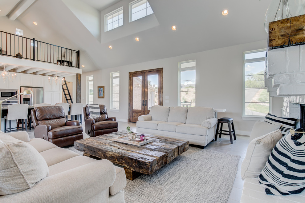 This is an example of a mid-sized country open concept living room in Dallas with grey walls, ceramic floors, a standard fireplace, a brick fireplace surround and grey floor.