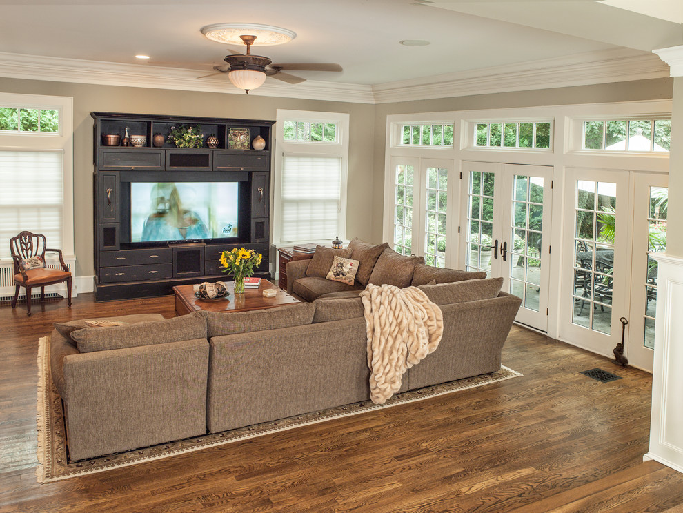 Photo of a large traditional open concept family room in New York with grey walls, dark hardwood floors, a built-in media wall and brown floor.