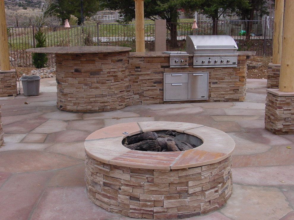 Mid-sized southwest backyard stone patio kitchen photo in Albuquerque with a pergola