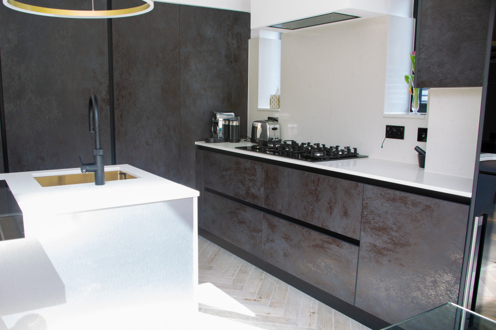 Mid-sized contemporary l-shaped kitchen in Essex with a single-bowl sink, glass benchtops, with island and black benchtop.