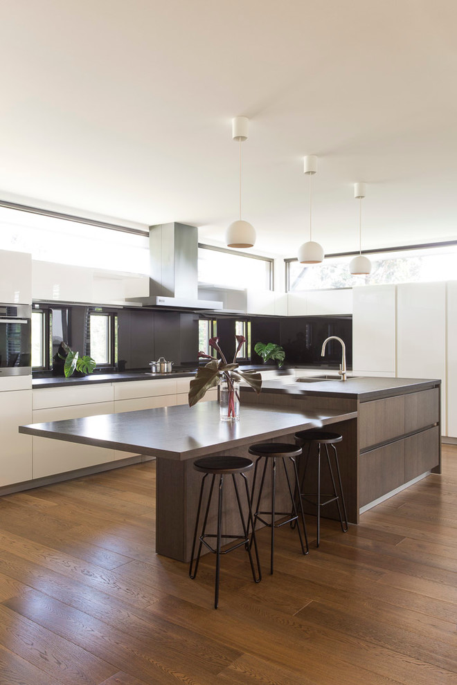 Photo of a contemporary l-shaped kitchen in Melbourne with flat-panel cabinets, white cabinets, medium hardwood floors and with island.