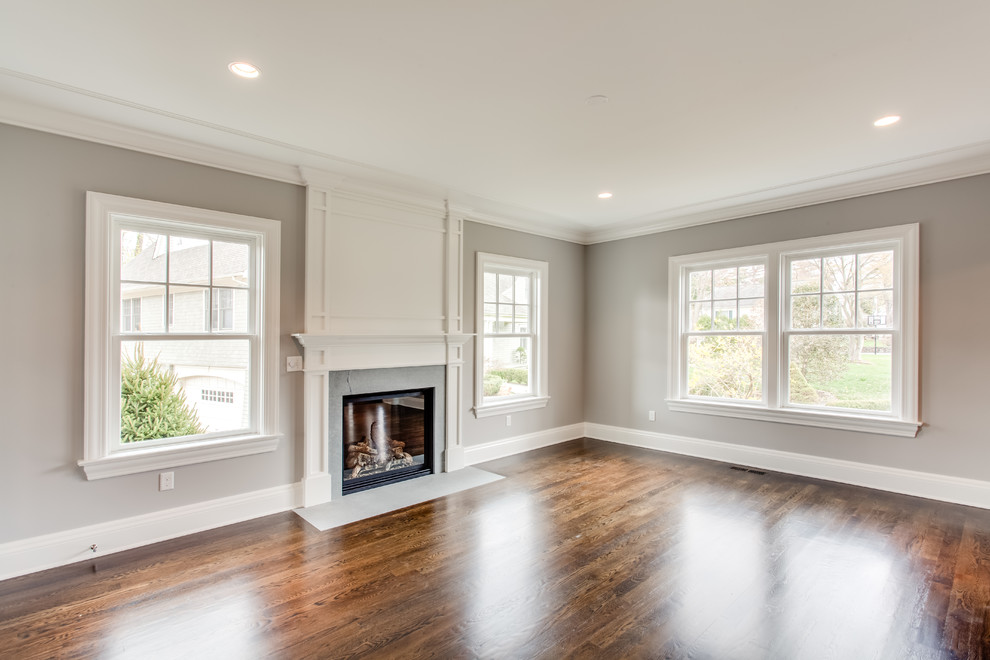 Large transitional formal enclosed living room in Other with grey walls, medium hardwood floors, a standard fireplace, a stone fireplace surround, no tv and brown floor.
