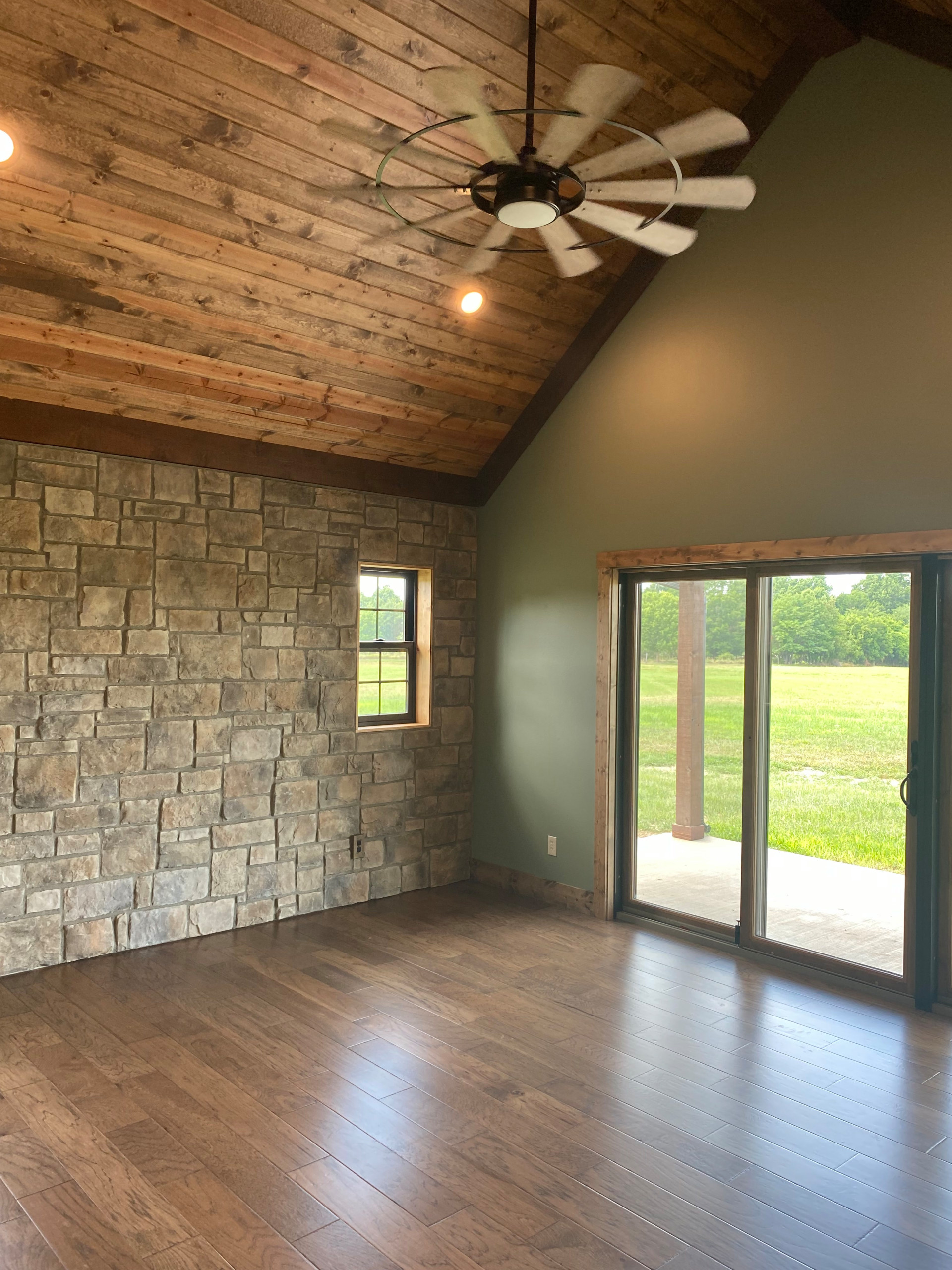 Master bedroom with stained carside ceiling, rock wall and slider doors