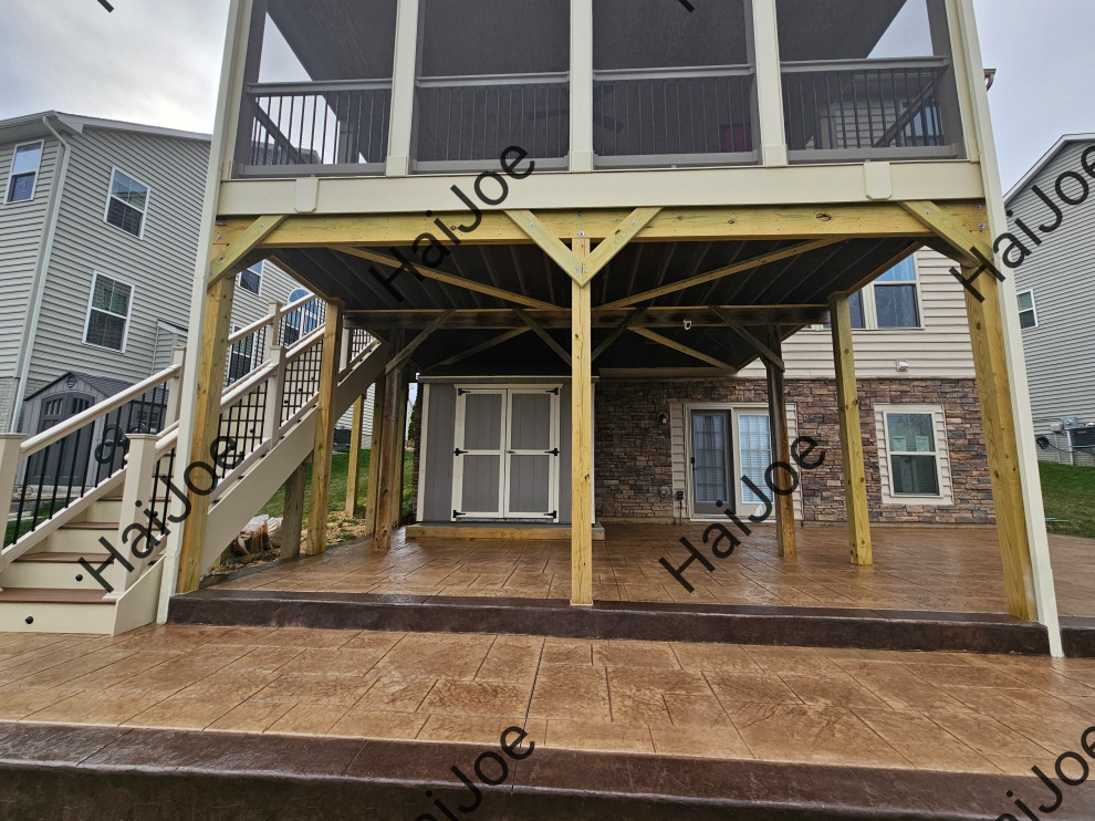 Photo of an expansive traditional backyard screened-in verandah in Other with stamped concrete, a roof extension and mixed railing.