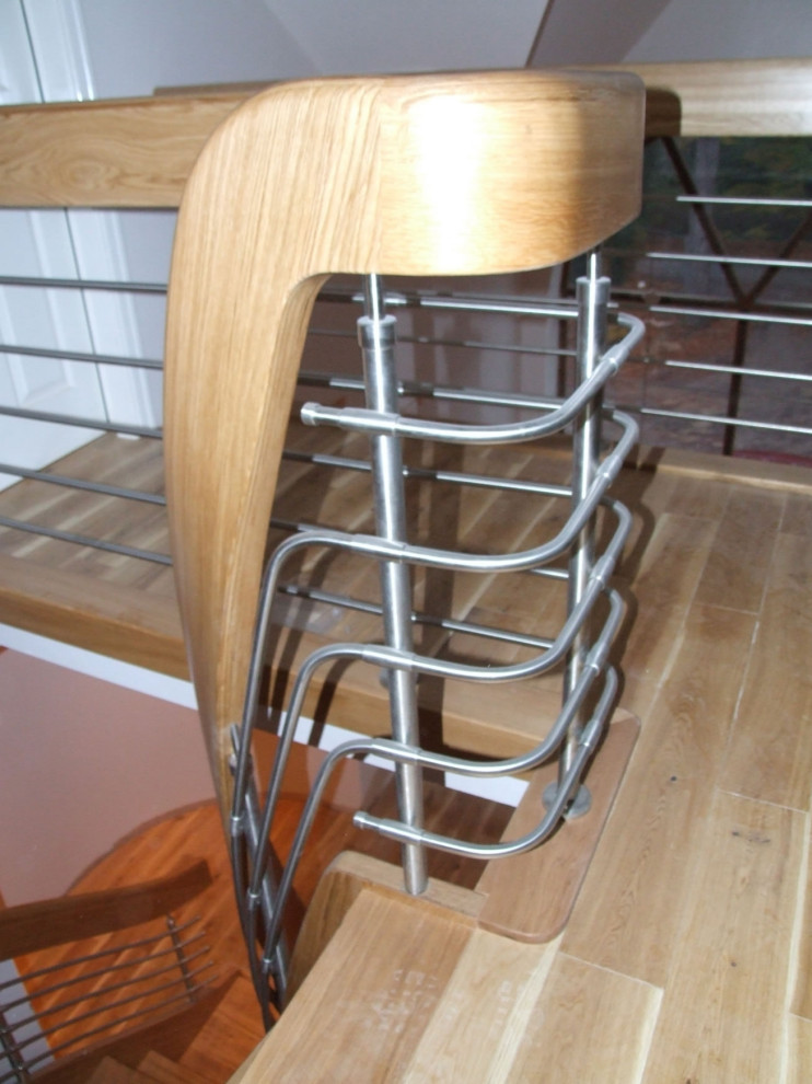 На фото: изогнутая деревянная лестница среднего размера в стиле модернизм с деревянными ступенями и перилами из смешанных материалов с